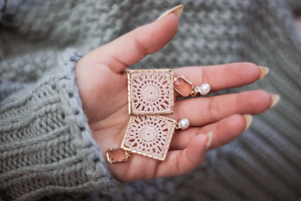 woman's hand holding a pair of crochet earrings