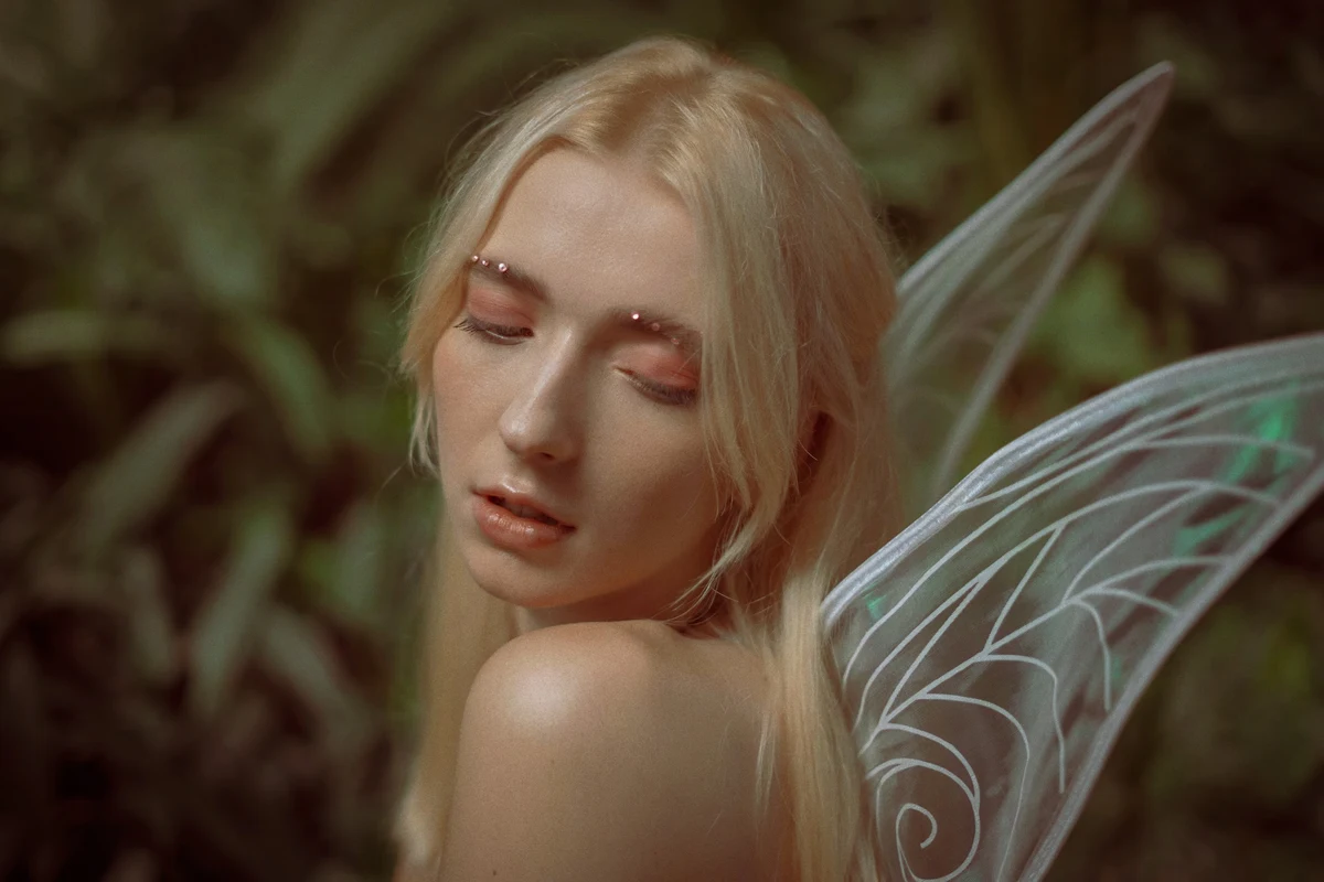 a portait of a beautiful woman with loose blonde hair an fairy wings behind her back